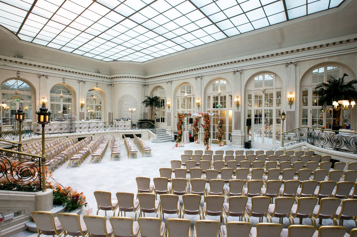 Glass-roofed event space set up for a wedding ceremony at the Waldorf Hilton