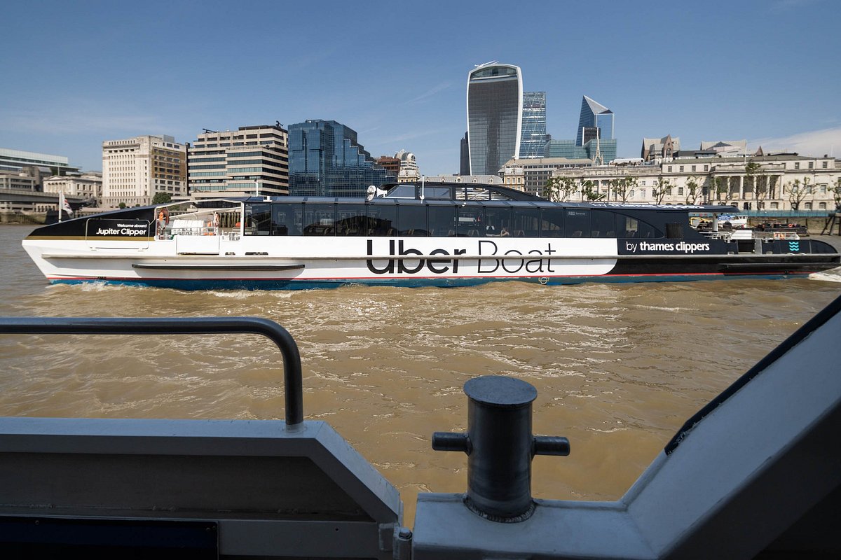 An Uber Boat by Thames Clippers passing the City of London skyline